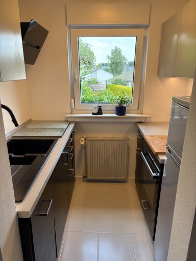 Moderne Küche mit Fenstern, Spüle und Elektrogeräten in neutralen Farben.